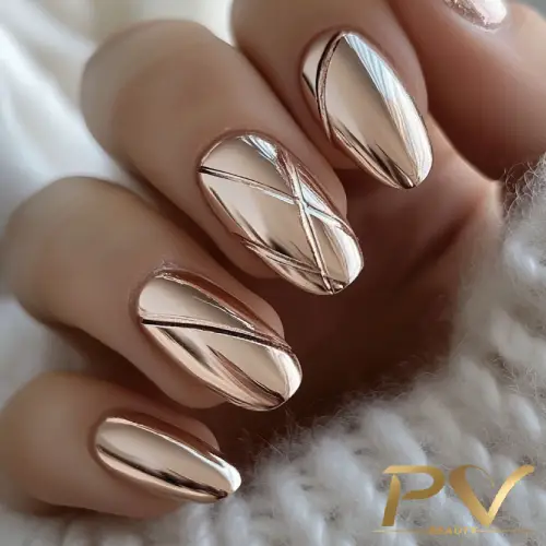 Unhas metálicas em tom dourado rosado com design geométrico de linhas finas.