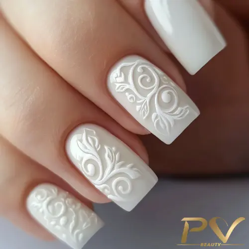 unhas-decoradas-branco-classicos-pv-beauty-32 Unhas com esmalte branco e decoração em relevo com padrões florais.