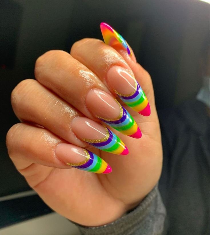 Mão com unhas longas e pontiagudas decoradas com listras coloridas em estilo arco-íris.
