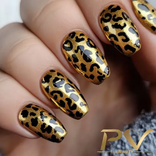 Unhas decoradas com estampa de oncinha em dourado e preto.