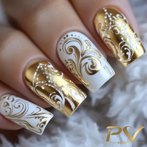 Unhas decoradas com esmalte dourado e branco, exibindo desenhos intrincados em estilo floral.