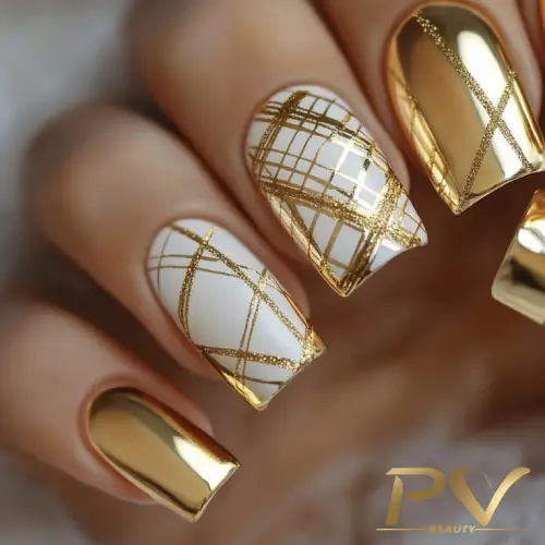 Unhas com esmalte dourado e branco, decoradas com linhas geométricas douradas.