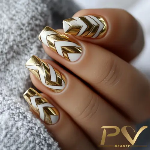 Unhas com decoração geométrica em dourado e branco, com padrão de setas. Fundo cinza e logotipo no canto inferior.