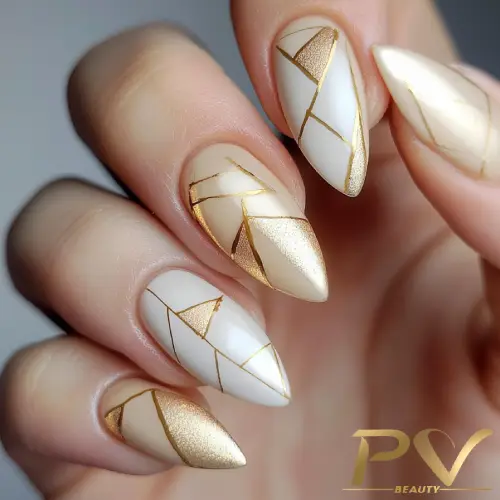 Unhas decoradas com esmalte branco e dourado, com design geométrico elegante e sofisticado.
