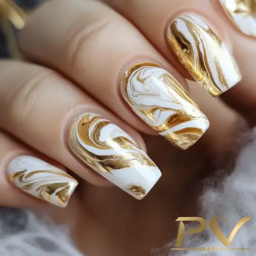 Unhas decoradas com esmalte marmorizado em branco e dourado, com acabamento brilhante.