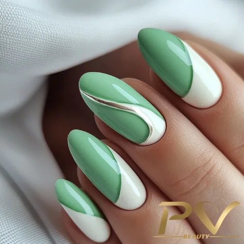 unhas-em-verde-decoradas-curvas-tom-sobre-tom-pv-beauty-18 Unhas decoradas com esmalte verde e branco, com detalhes metálicos prateados, em fundo claro.
