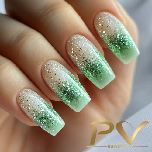 Unhas verdes com efeito ombré e glitter, criando um visual elegante e moderno.