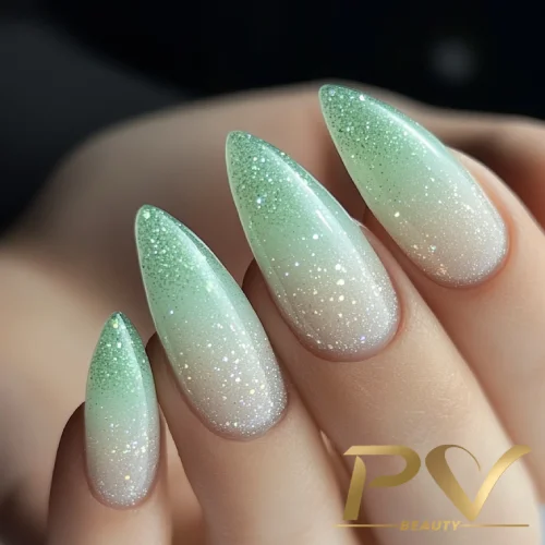 unhas-em-verde-decoradas-ombre-glitter-pv-beauty-13 Unhas em formato stiletto com esmalte degradê verde e glitter.