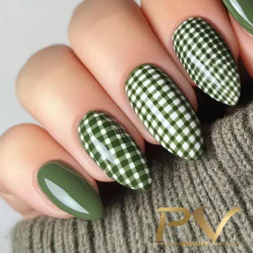 unhas-em-verde-decoradas-xadrez-vichy-pv-beauty-08 Unhas decoradas com esmalte verde sólido e estampa xadrez verde e branco, próximas a um tecido cinza.