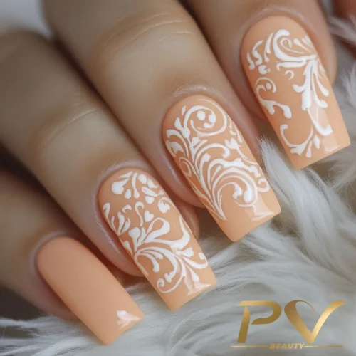 unhas-laranja-decoradas-arabescos-pv-beauty-02 Unhas decoradas com esmalte laranja claro e detalhes brancos florais sobre superfície macia e clara.