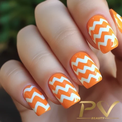 unhas-laranja-decoradas-chevron-pv-beauty-09 Unhas com esmalte laranja e padrão zigue-zague branco.
