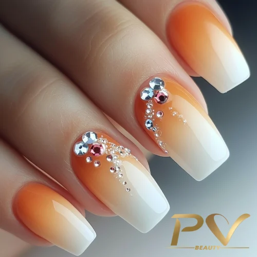unhas-laranja-decoradas-degrade-pedrarias-pv-beauty-03 Unhas decoradas com esmalte laranja e branco, adornadas com pequenas pedras brilhantes e detalhes metálicos.