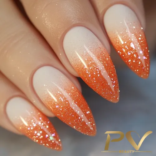 unhas-laranja-decoradas-ombre-glitter-pv-beauty-04 Unhas pontiagudas com esmalte degradê em tons de laranja e branco, adornadas com brilho.