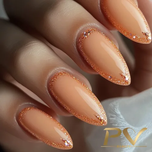 unhas-laranja-decoradas-pastel-glitter-brilho-pv-beauty-17 Unhas em formato stiletto com esmalte nude e bordas com brilho dourado.