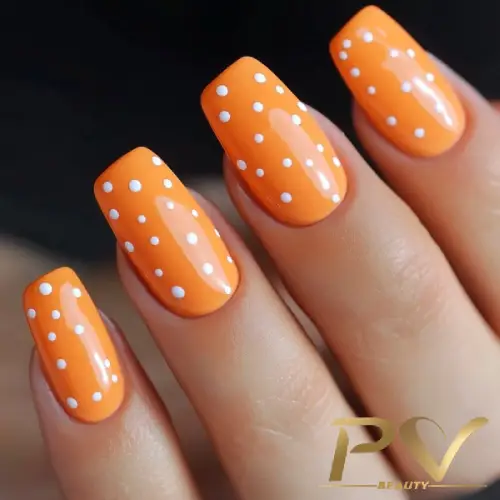 unhas-laranja-decoradas-poa-bolinhas-pv-beauty-28 Unhas com esmalte laranja e bolinhas brancas, exibindo um design de nail art.