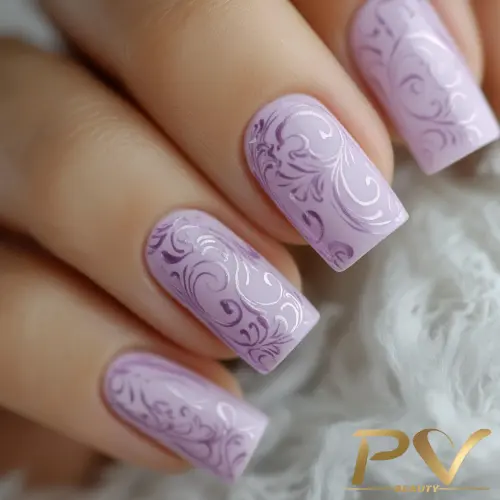 Unhas decoradas com esmalte lilás e desenhos de arabescos, sobre fundo claro e textura macia.