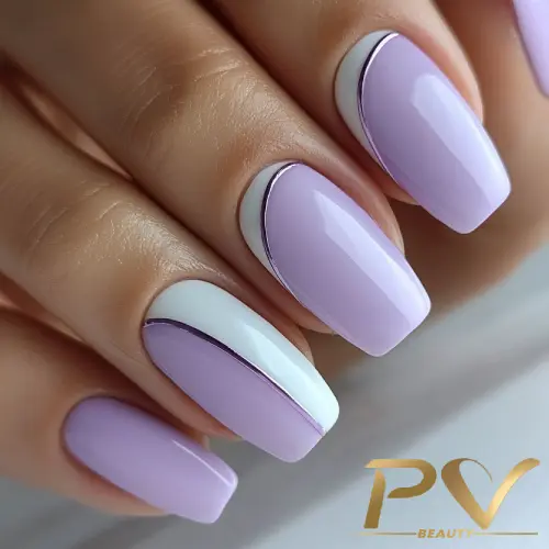 Unhas decoradas com esmalte lilás e branco, com detalhes metálicos finos.