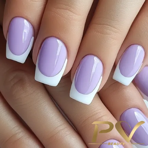 Unhas decoradas com esmalte lilás e pontas brancas, mostrando uma manicure bem cuidada.