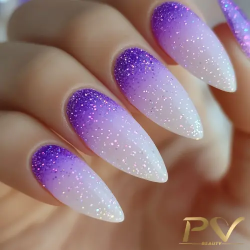 Unhas compridas com esmalte degradê roxo e glitter.