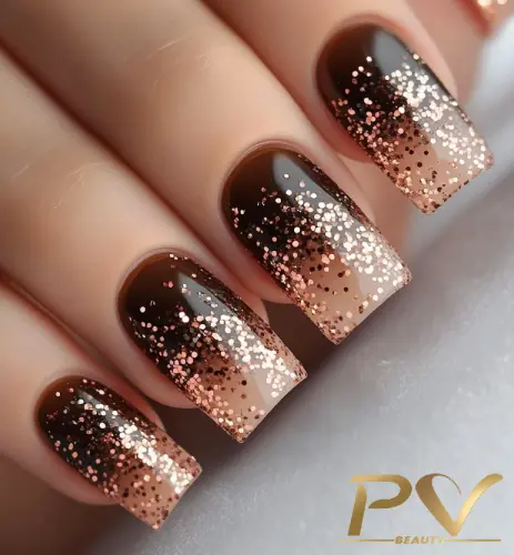 unhas-marrons-decoradas-glitter-degrade-pv-beauty-33 Unhas esmaltadas em tons de marrom com glitter dourado, criando um efeito degradê elegante.