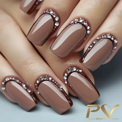 unhas-marrons-decoradas-strass-pv-beauty-29 Unhas com esmalte marrom e decoração de pedrarias brilhantes nas bordas, em estilo elegante.