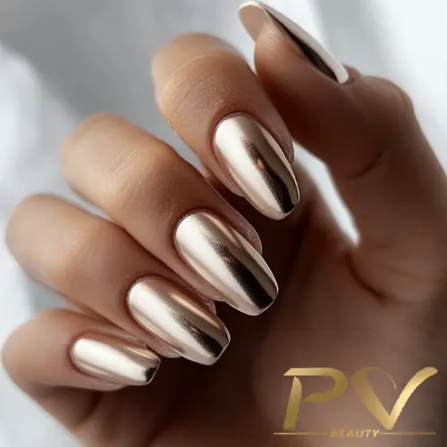 unhas-marrons-esmalte-metalizado-decoradas-pv-beauty-27 Mão com unhas longas e esmalte metálico dourado, exibindo brilho intenso. Fundo desfocado.