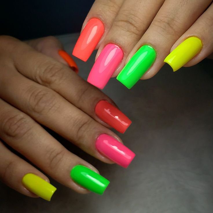 Unhas longas com esmalte neon em cores variadas: laranja, rosa, verde e amarelo.