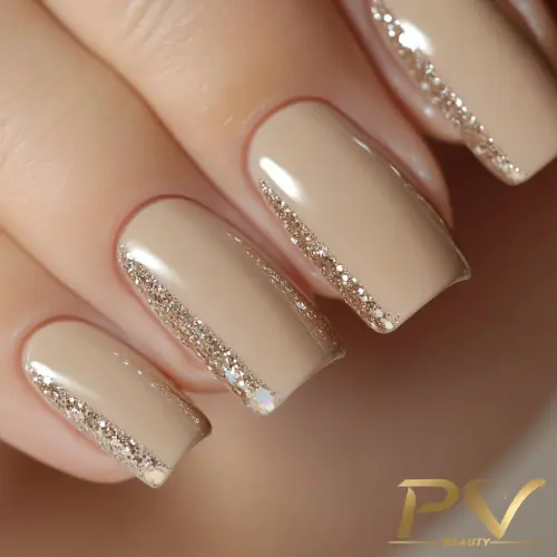 unhas-nude-glitter-lindas-decoradas-pv-beauty-16 Unhas com esmalte bege e detalhe de glitter dourado nas laterais, em close-up.