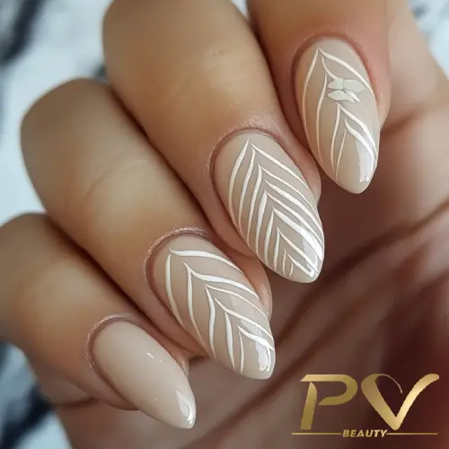 unhas-nude-linhas-finas-em-branco-decoradas-pv-beauty-15 Mão com unhas decoradas em tom nude, apresentando desenhos de folhas brancas. Logo "PV Beauty" no canto inferior.