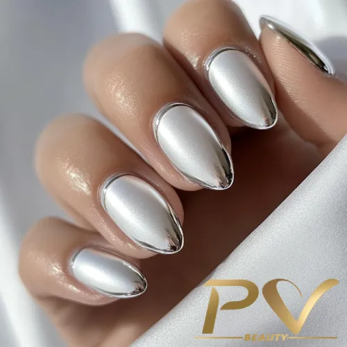 unhas-prata-brilho-decoradas-pv-beauty-10 Mão com unhas alongadas e esmaltadas em prata metálico, segurando tecido branco. Logo PV Beauty no canto.