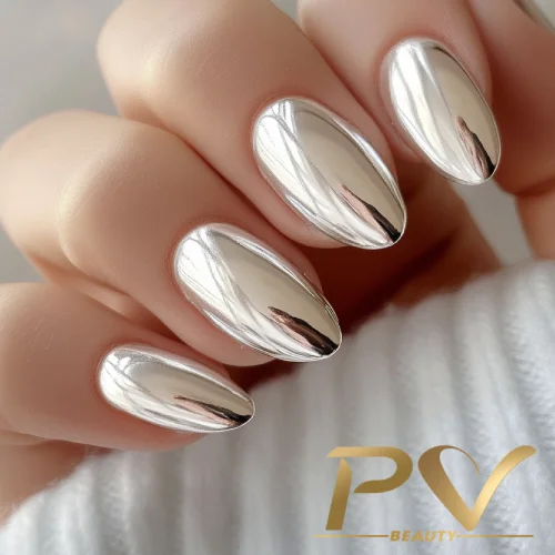 unhas-prata-cromada-metalizada-decoradas-pv-beauty-08 Unhas com esmalte prateado metálico refletindo luz, com fundo desfocado e logotipo no canto inferior direito.