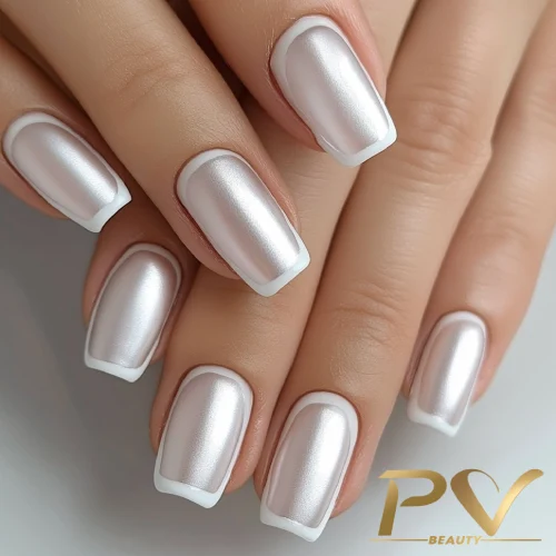 unhas-prata-fosca-decoradas-pv-beauty-24 Mãos com unhas quadradas pintadas de esmalte prateado e bordas brancas, com logotipo PV Beauty no canto inferior direito.
