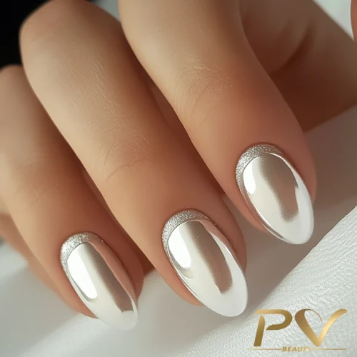 unhas-prata-francesinha-invertida-decoradas-pv-beauty-23 Unhas com esmalte prateado brilhante e detalhes prateados na base, em um fundo claro.