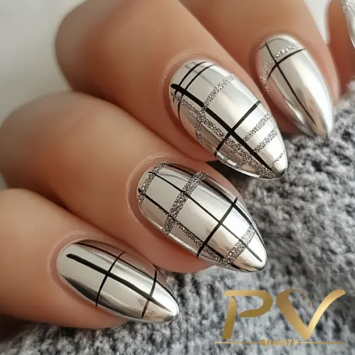 unhas-prata-xadrez-decoradas-pv-beauty-30 Unhas metálicas prateadas com design de linhas pretas e prateadas sobre um fundo cinza texturizado.
