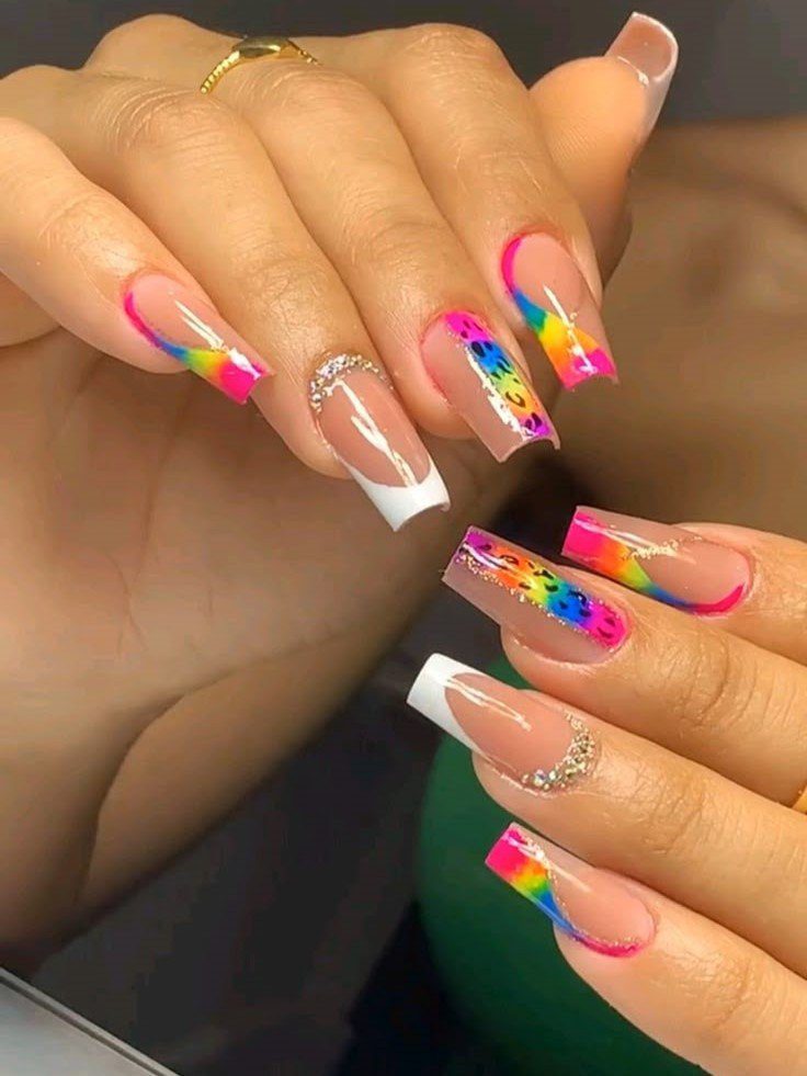 Unhas com design colorido e detalhes em brilhos, combinando pontas francesas e padrões vibrantes.
