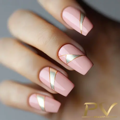 Unhas quadradas pintadas de rosa claro com detalhes em linhas douradas diagonais e design geométrico.