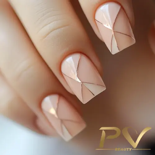 Unhas decoradas com esmalte nude e design geométrico em linhas douradas.