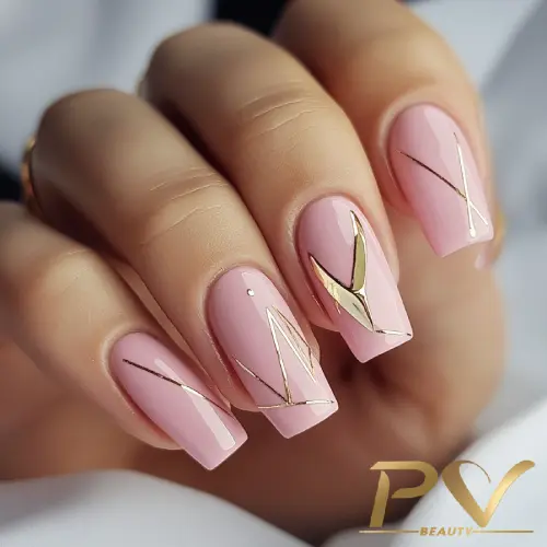Unhas com esmalte rosa claro e detalhes metálicos dourados em design geométrico.