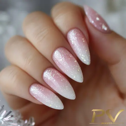 Unhas decoradas em estilo ombré rosa e branco, com glitter, formato stiletto.