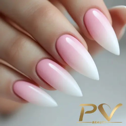 Unhas longas com esmalte em degradê rosa e branco, em formato pontiagudo.