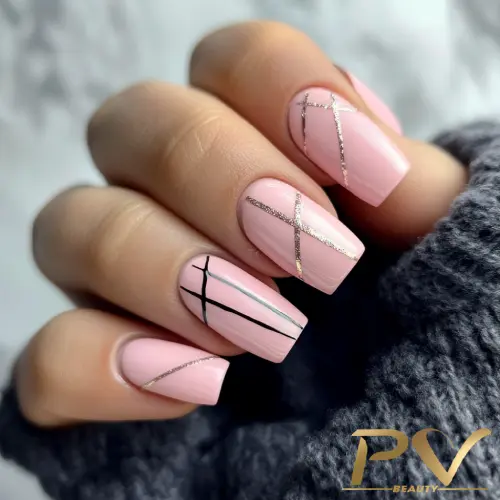 Mão com unhas pintadas de rosa claro e decoradas com linhas finas pretas e prateadas.