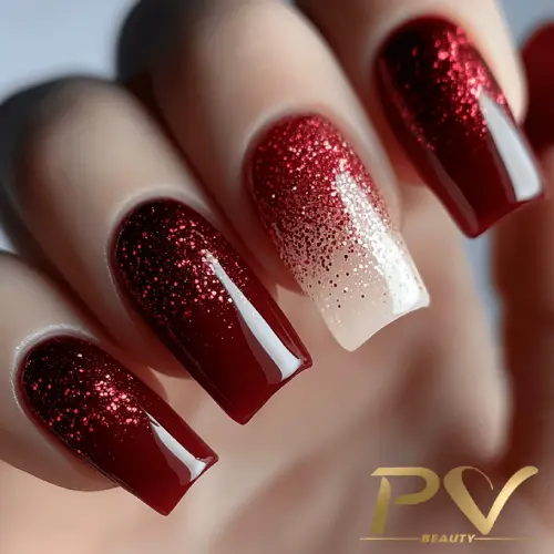 unhas-vinho-decoradas-designer-de-unhas-pv-beauty-01 Unhas decoradas com esmalte vermelho escuro e glitter, destacando um efeito degradê em uma das unhas.