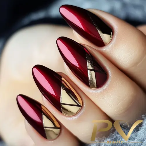 unhas-vinho-decoradas-detalhes-ouro-pv-beauty-04 Unhas com esmalte vermelho metálico e detalhes geométricos dourados em um fundo escuro.