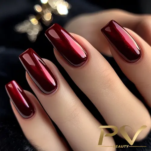 unhas-vinho-decoradas-esmaltacao-metalizada-pv-beauty-28 Unhas longas e quadradas com esmalte vermelho escuro brilhante, em fundo desfocado.