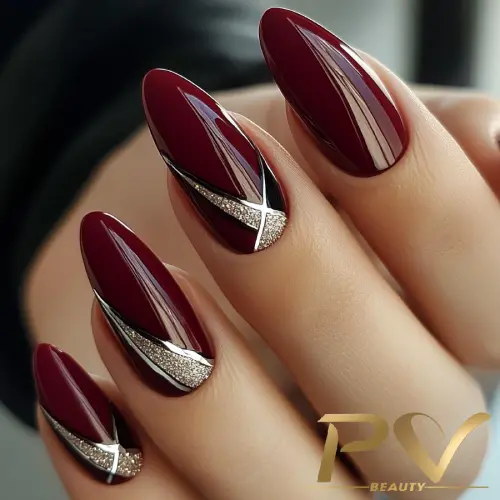 unhas-vinho-decoradas-prata-pv-beauty-23 Unhas com esmalte bordô, detalhes prateados e pretos, em formato oval, destacando um design sofisticado e elegante.