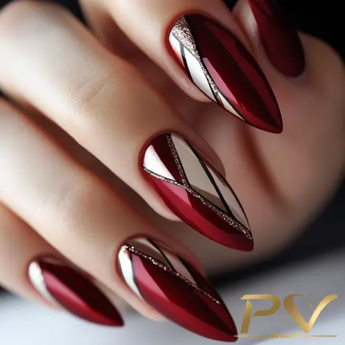 unhas-vinho-geometricas-decoradas-pv-beauty-26 Unhas decoradas com esmalte vermelho, detalhes geométricos em preto e branco, e linhas prateadas brilhantes.