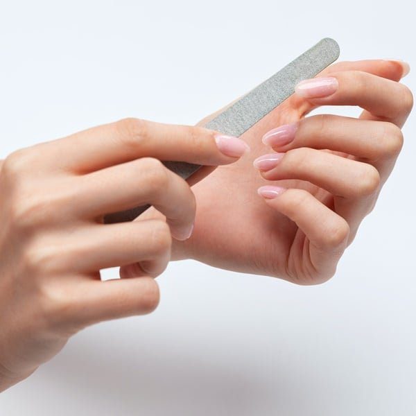 Mulher mantendo os cuidados essenciais das suas unhas naturais lixando suas unhas.