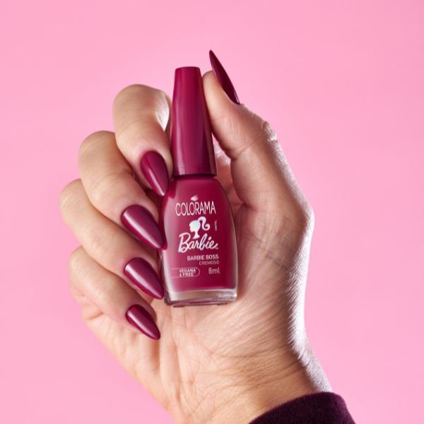 esmalte-barbie-boss-colorama-barbie Foto de mão com o esmalte Barbie Boss nas unhas segurando o potinho do esmalte para mostrar para a câmera.