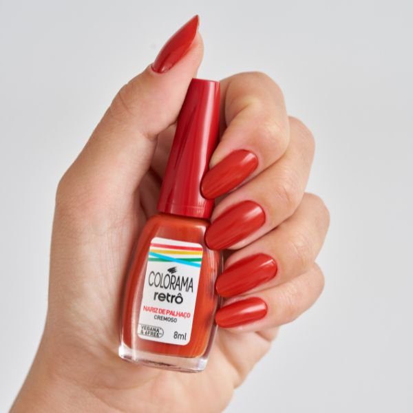 Mão segurando o esmalte Nariz de Palhaço da Coleção Colorama Retrô.